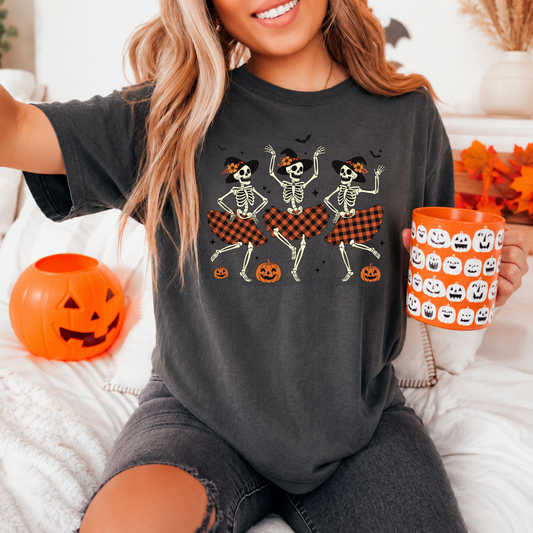 Woman wearing an oversized charcoal grey dancing skeleton Halloween graphic tee with a pumpkin bucket.
